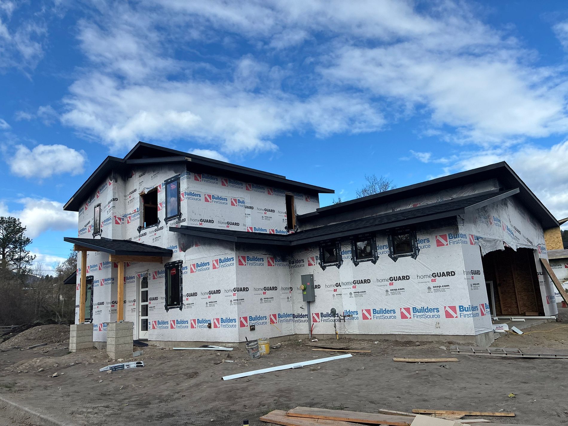 Two-story home under construction wrapped in house wrap, awaiting its new roof