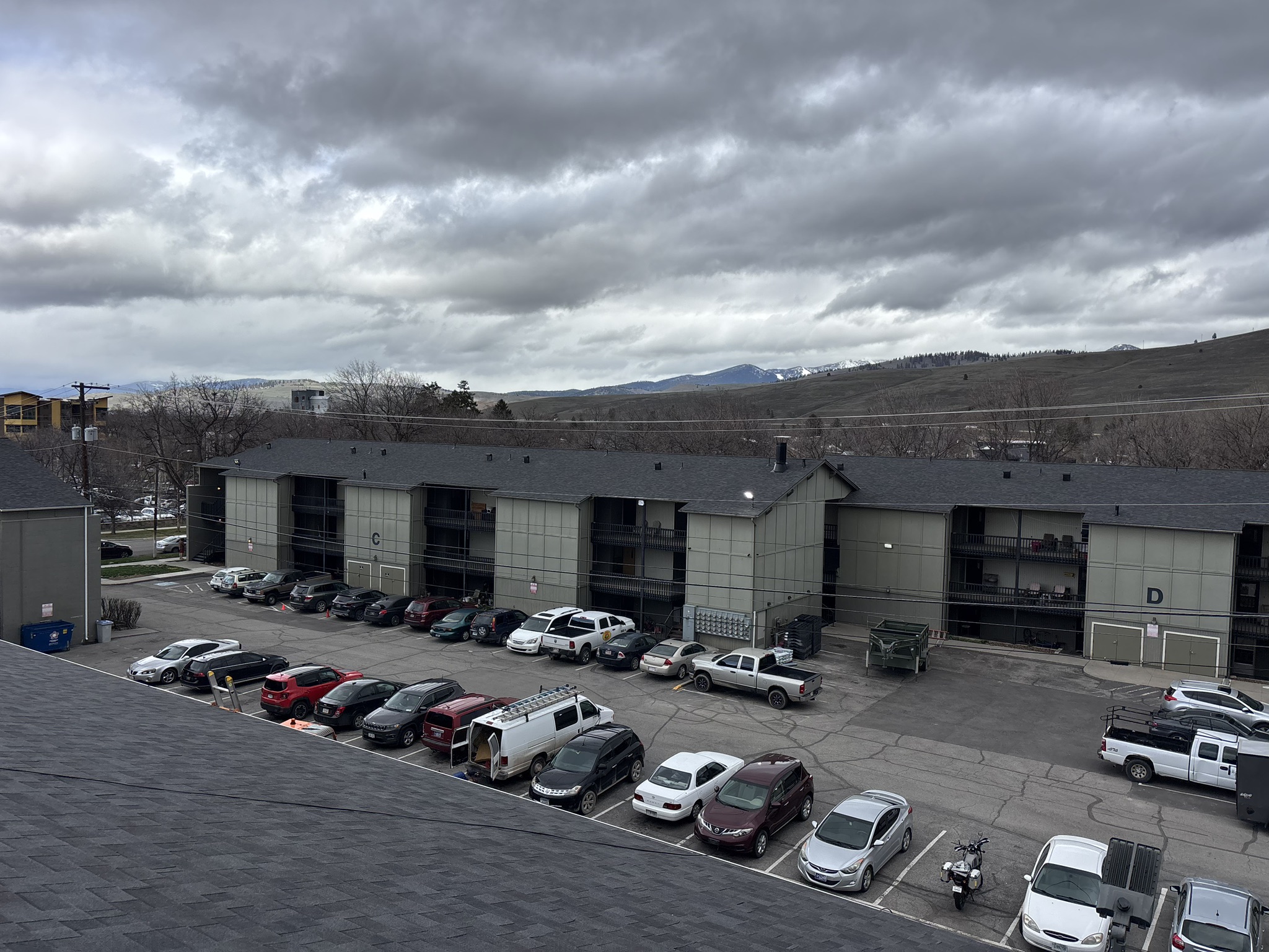Aerial view of a multi-building apartment complex with low-slope roofs and a parking lot.