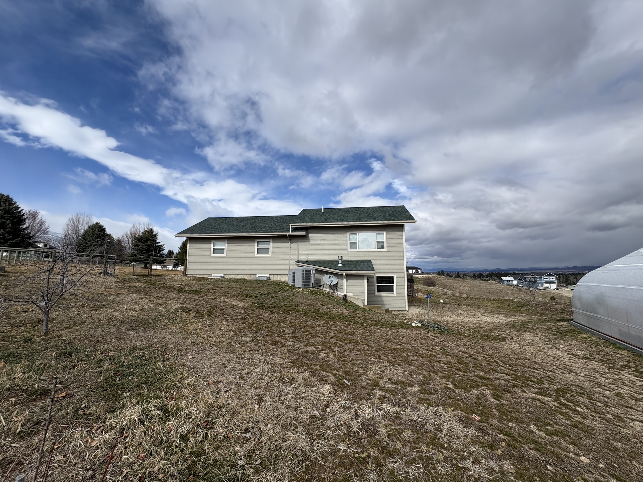 Single-story home with a green roof set on an open field near Columbus, MT