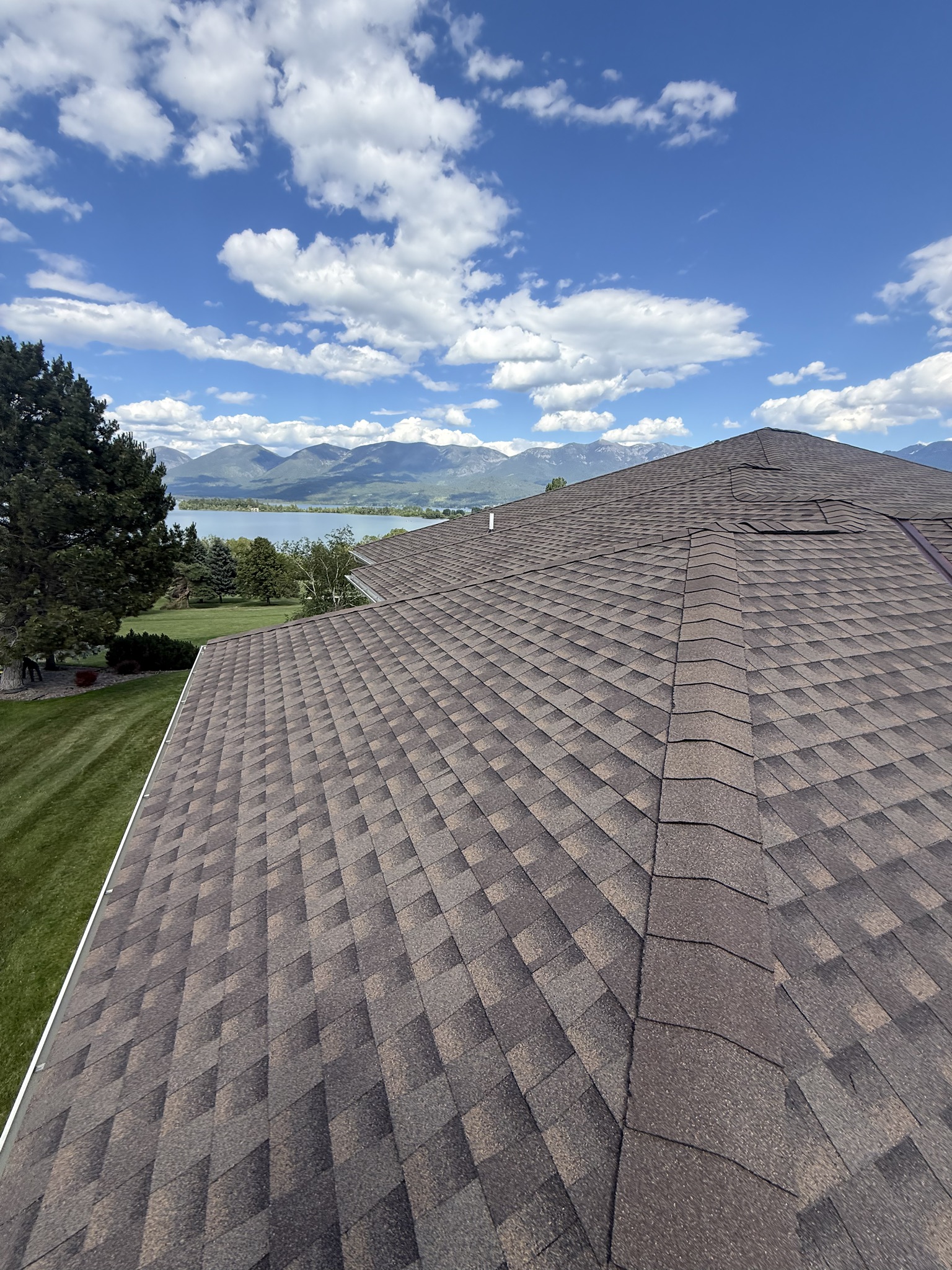 Brown architectural shingle roof with a mountain and lake view beyond in Montana