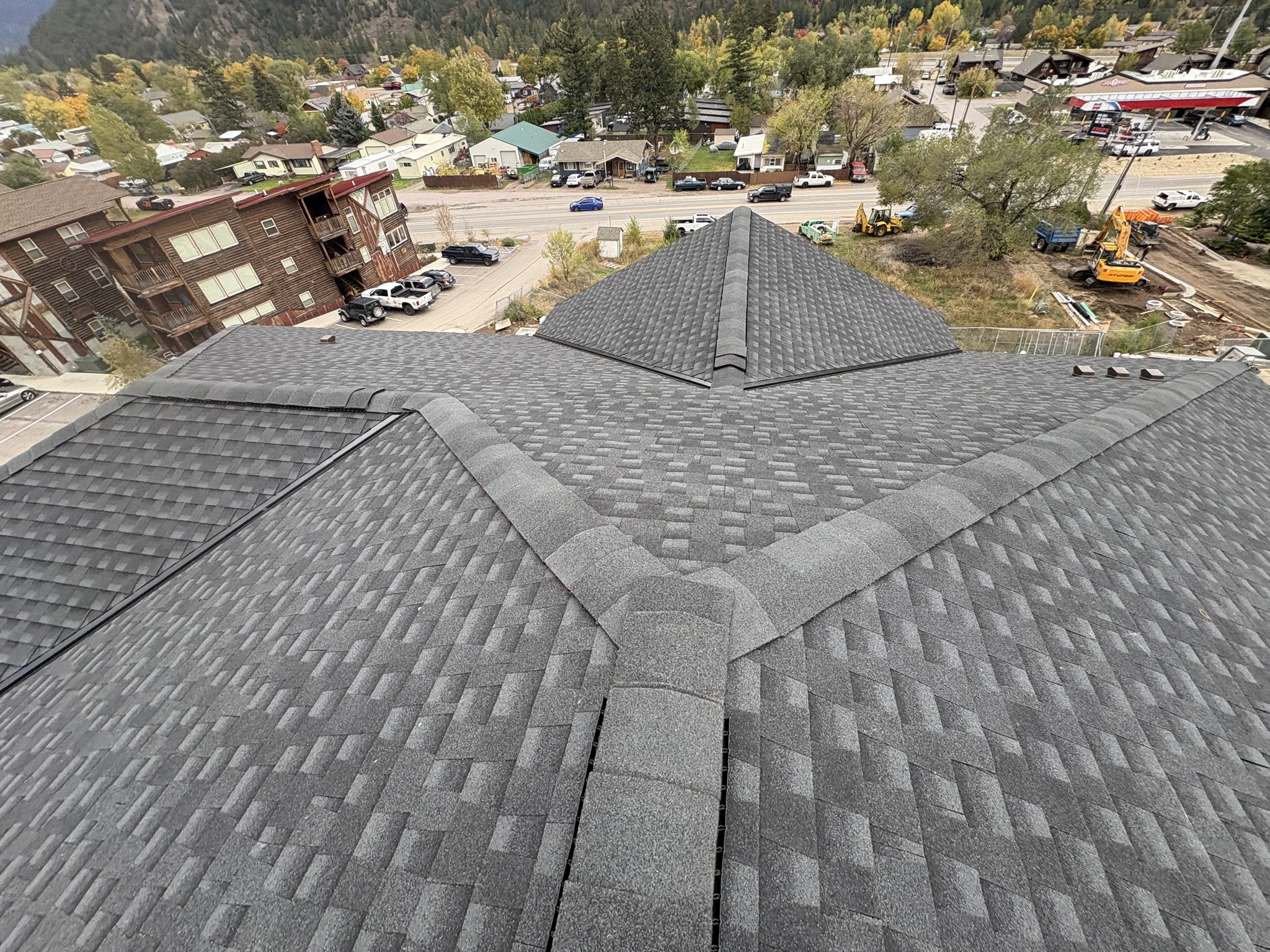 Aerial view of a gray architectural shingle hip roof above a valley town.